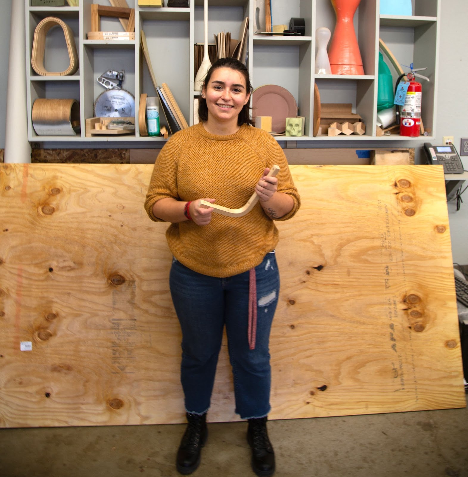 Juliana holding a piece of wood in the art studio