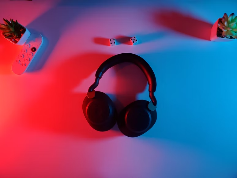 A pair of black wireless headphones on a table with blue and red lighting