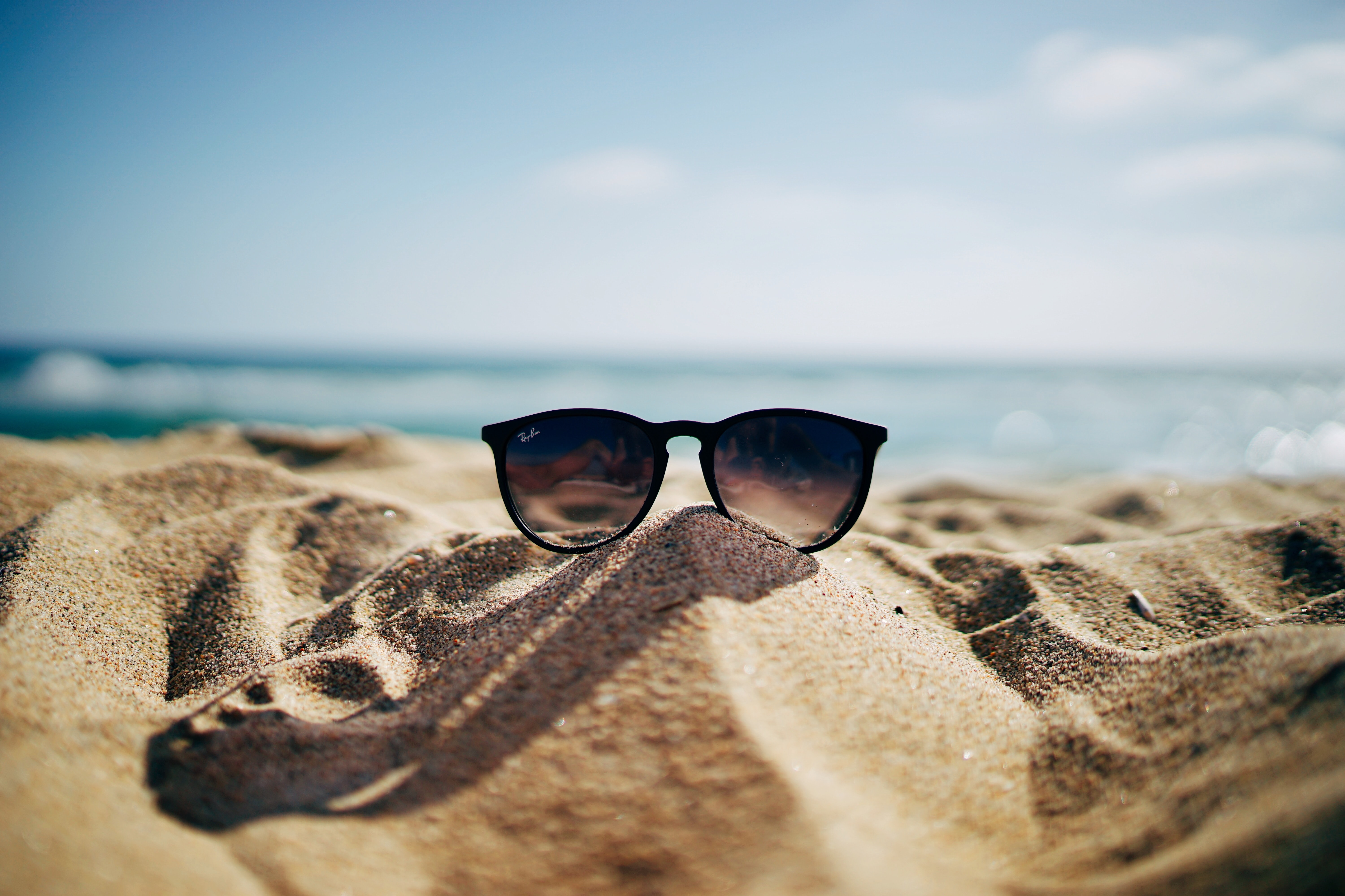 Sunglasses on the sand at the beach in front of the ocean